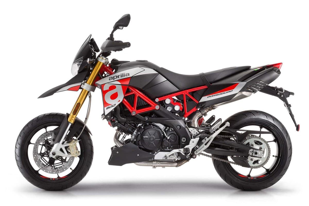 2020 Aprilia Dorsoduro 900 supermoto in black and white with red trellis frame, left-side studio profile showing gold forks and twin-spar chassis