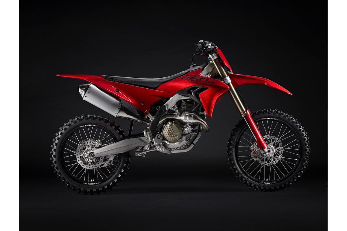 2027 Ducati Desmo250 MX motocross bike in red and black, right-side studio profile showing the exposed trellis-style frame and gold-tone forks
