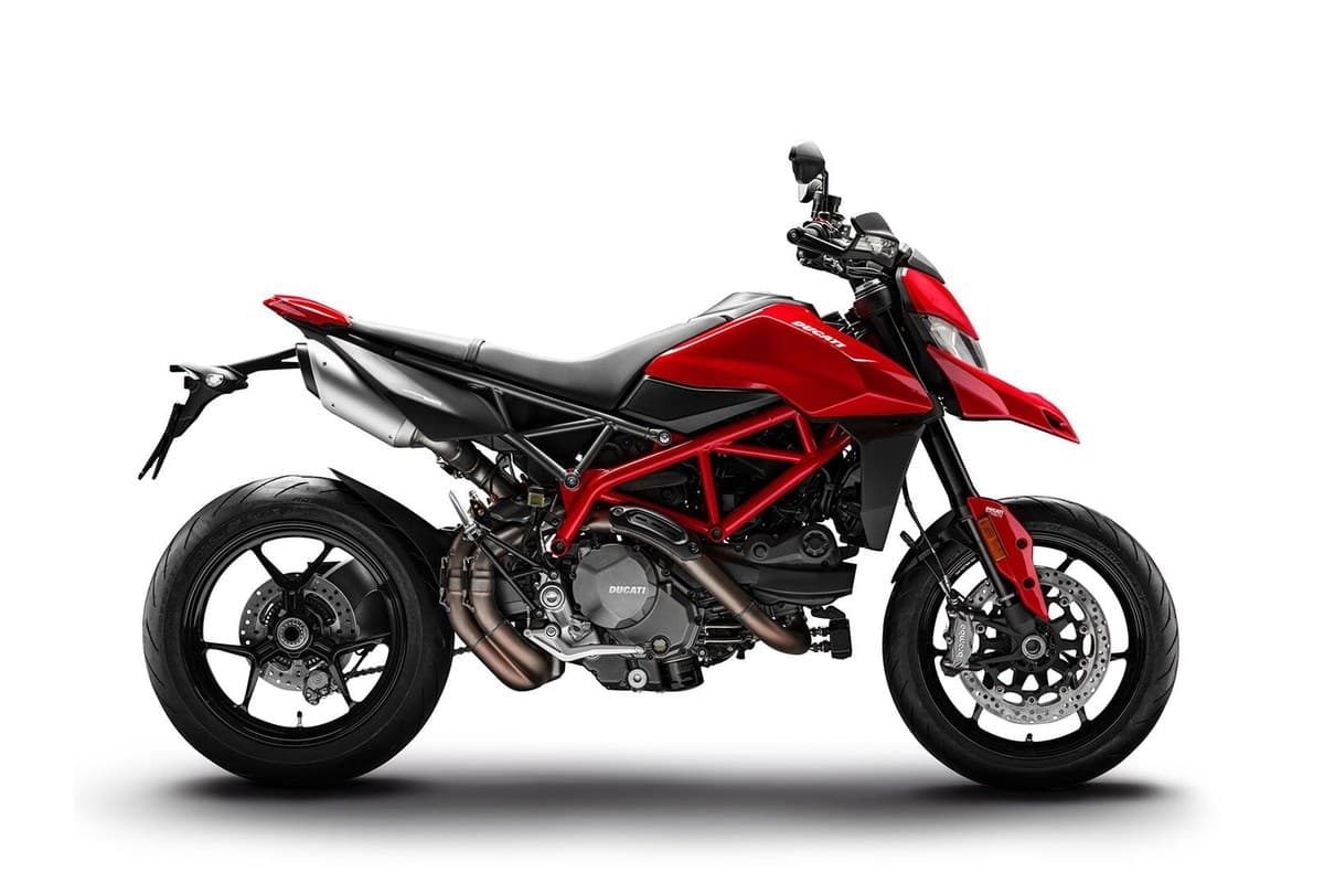 2025 Ducati Hypermotard 950 in red, left-side studio profile showing the red trellis frame, twin underseat exhausts and spoked cast wheels