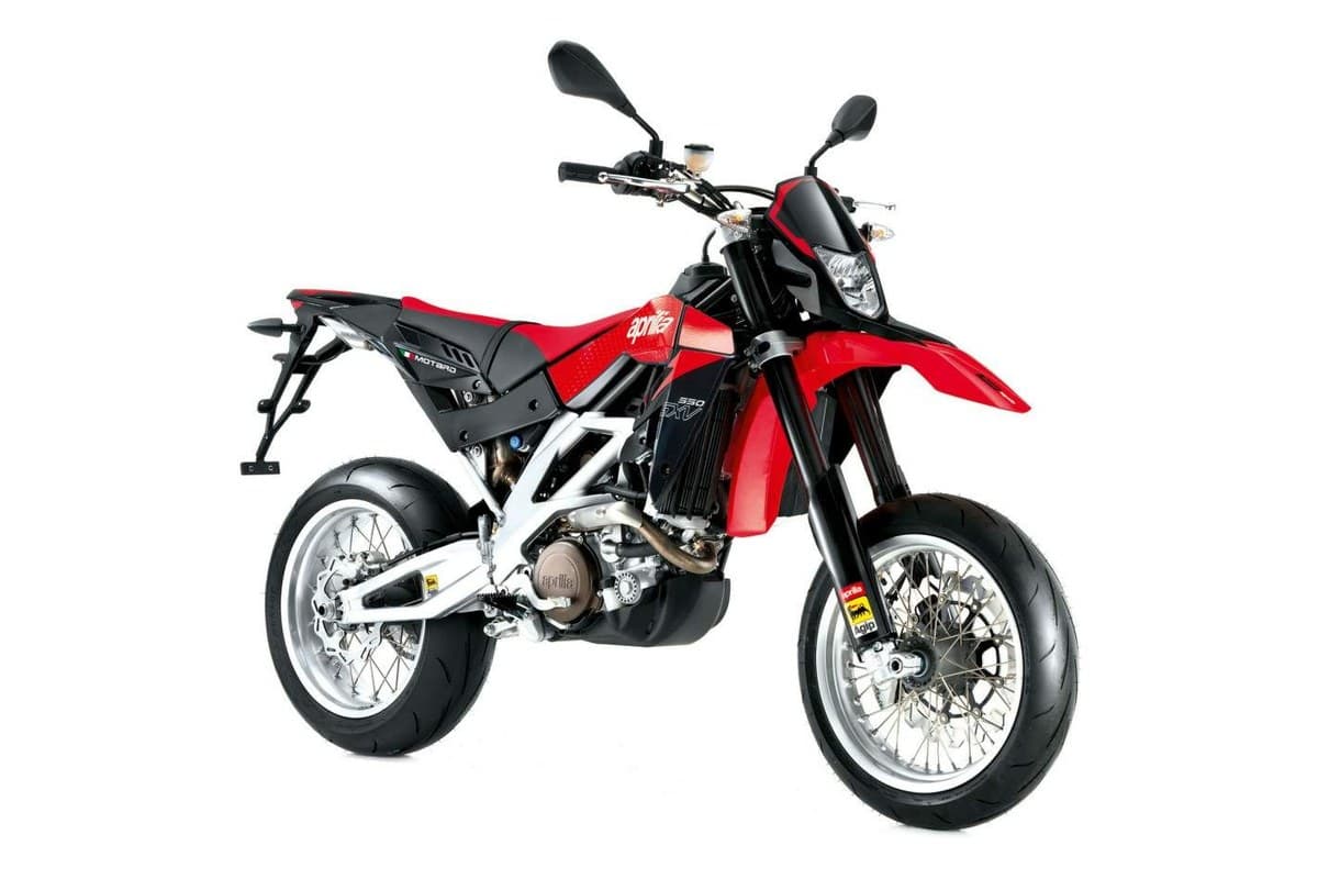 Aprilia SXV 550 in red and black, front three-quarter studio view highlighting the compact headlight, V-twin engine and Motard side graphics
