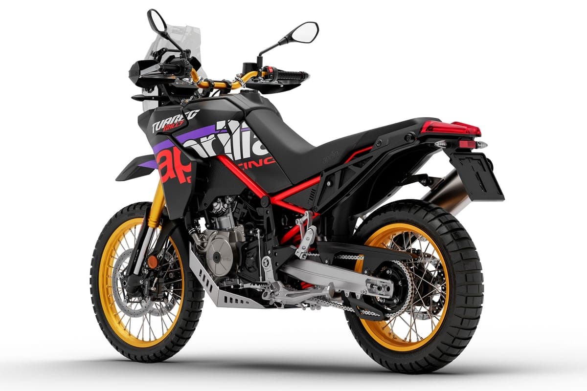 Aprilia Tuareg 660 Rally rear three-quarter studio view highlighting the red trellis-style frame, aluminum skid plate and twin exhaust can