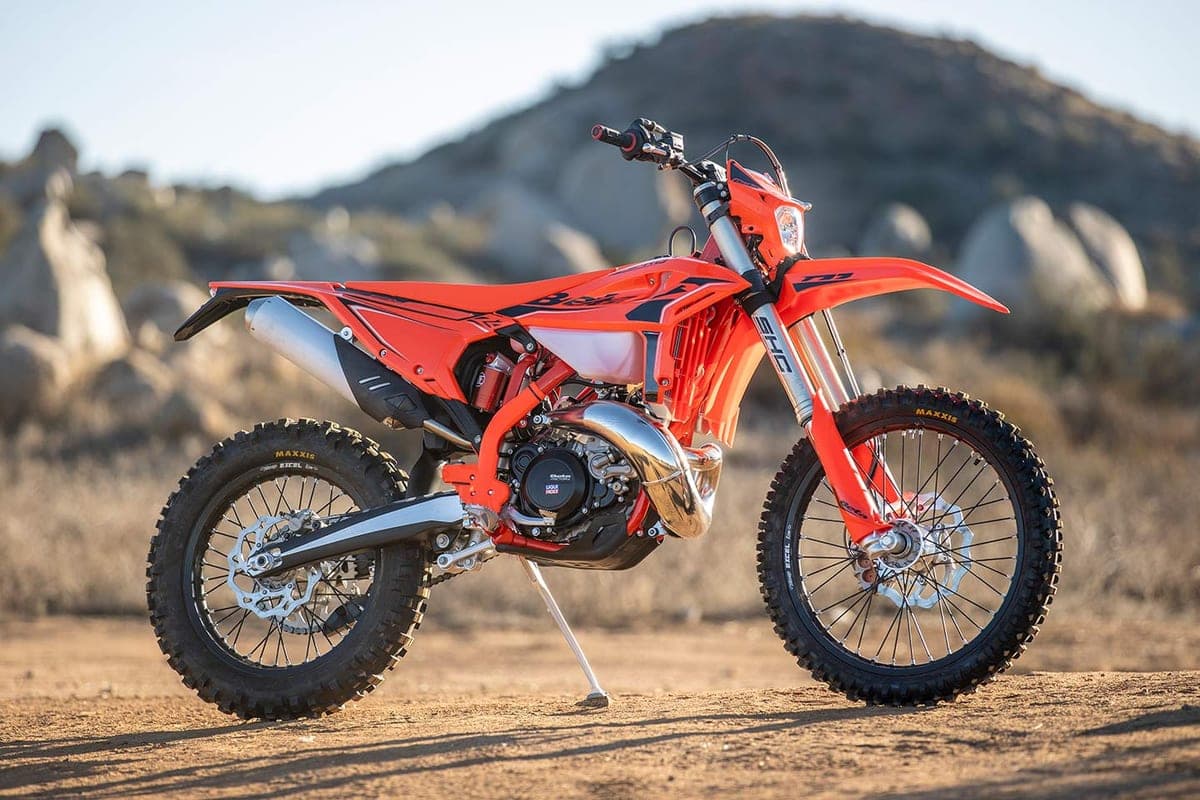 Beta 250 RR X-Pro parked on its kickstand on a dirt trail with rocky hills behind it, showing the WP-style shock, spoked wheels and Maxxis knobby tires