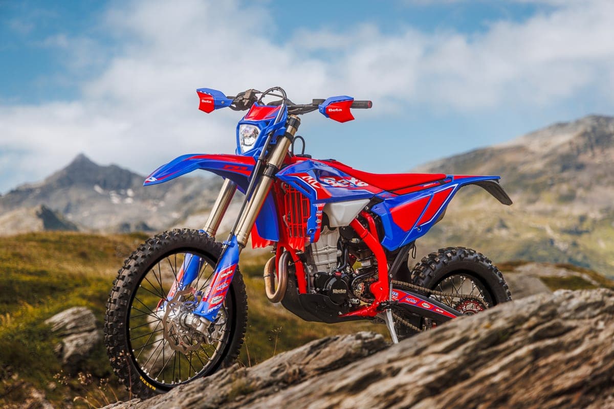 Beta 350 RR Race perched on a rocky outcrop, front three-quarter view against alpine peaks highlighting the handguards and radiator shrouds