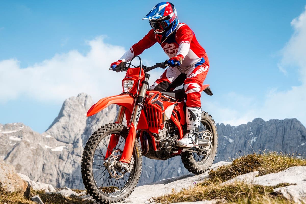 Rider in red and white Beta gear riding the 350 RR X-Pro up a rocky mountain trail with jagged peaks in the background