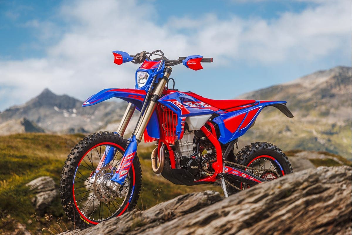 Beta 480 RR Race parked on a rocky outcrop with mountains behind, front three-quarter view highlighting red handguards, headlight and radiator shrouds