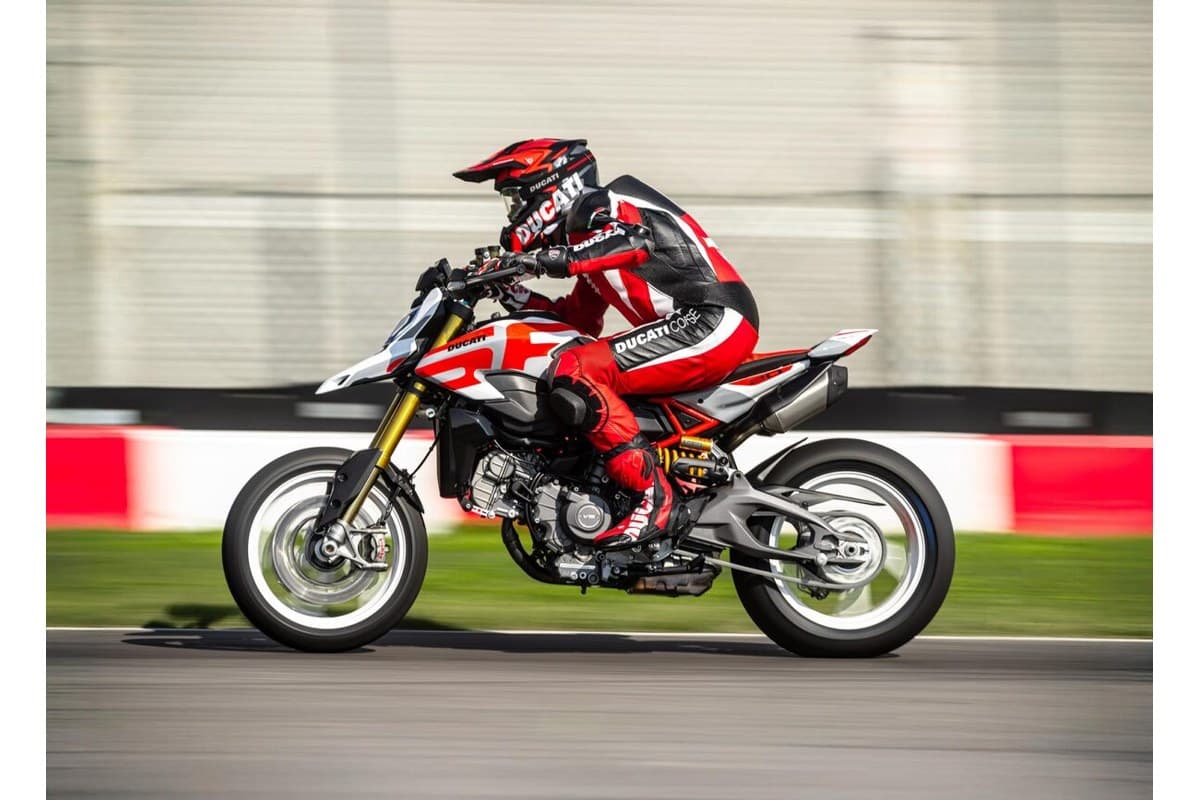 Rider in red and white Ducati leathers leaning into a track corner on the Hypermotard V2 SP, front tire lofting off the tarmac