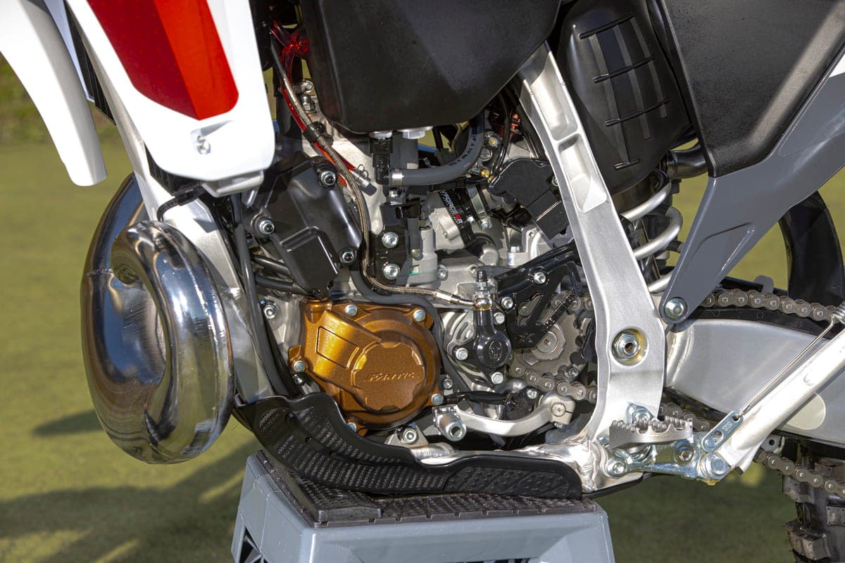 Close-up of the Fantic XE 300's two-stroke engine bay, showing the gold clutch cover, chrome expansion chamber and aluminum perimeter frame