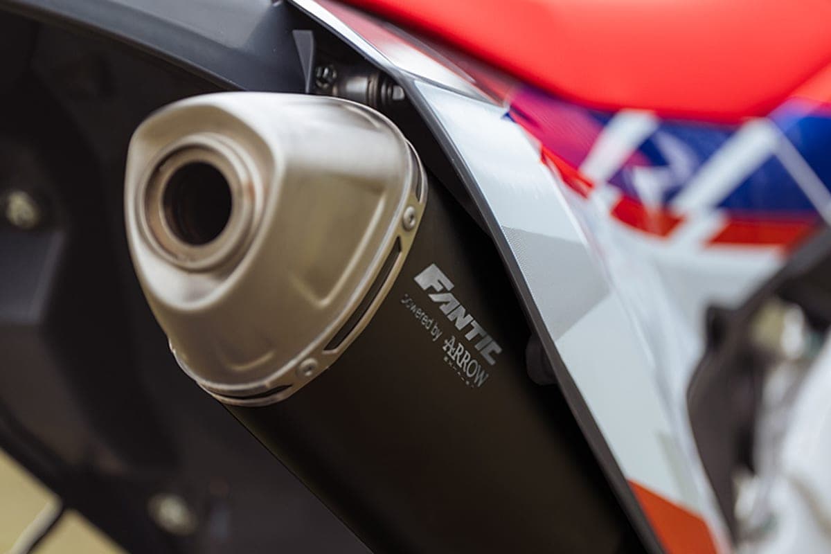 Fantic XEF 250 TL detail shot of the stainless Arrow slip-on exhaust muffler against black bodywork and red-white-blue side panel