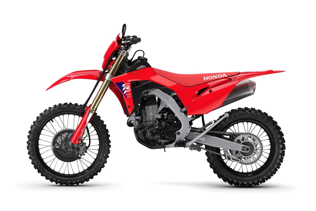 2027 Honda CRF450X in red, left-side studio profile with CRF graphics on the shrouds and spoked wheels with knobby tires
