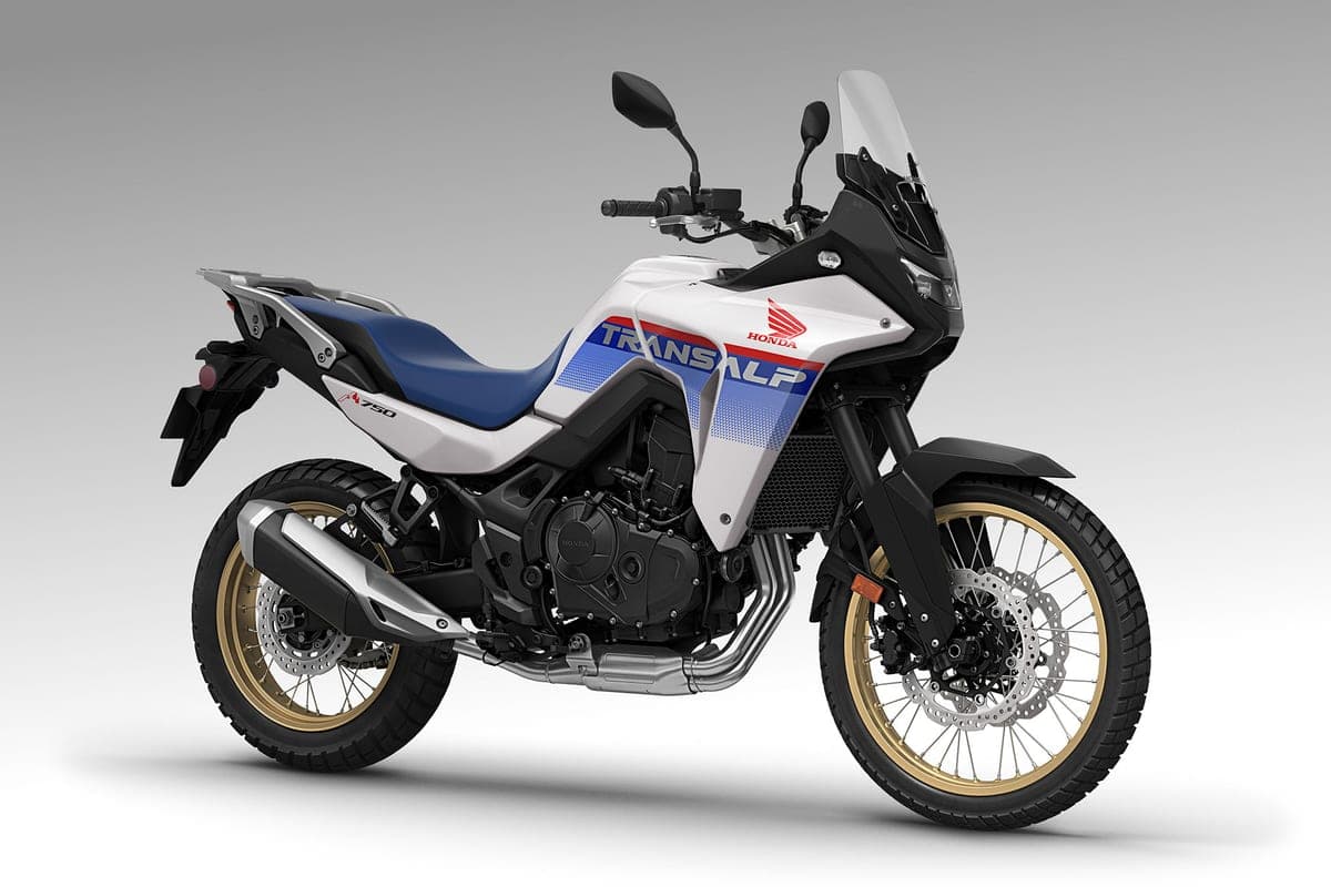 Honda Transalp XL750 in white, blue and red livery, front three-quarter studio view highlighting the tall windscreen, engine guard and stacked headlight