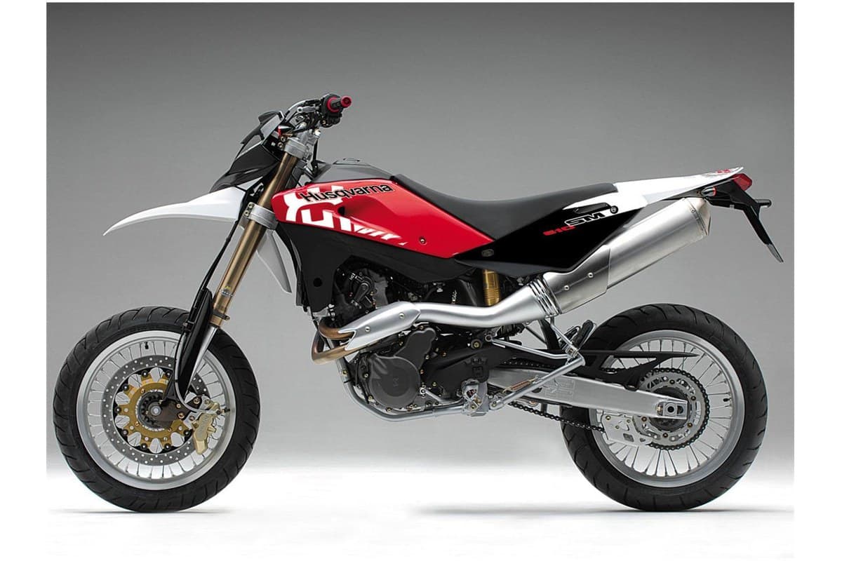 Husqvarna SM 610 left-side studio view highlighting the upswept silver muffler, tank graphics and open-spoke supermoto wheels