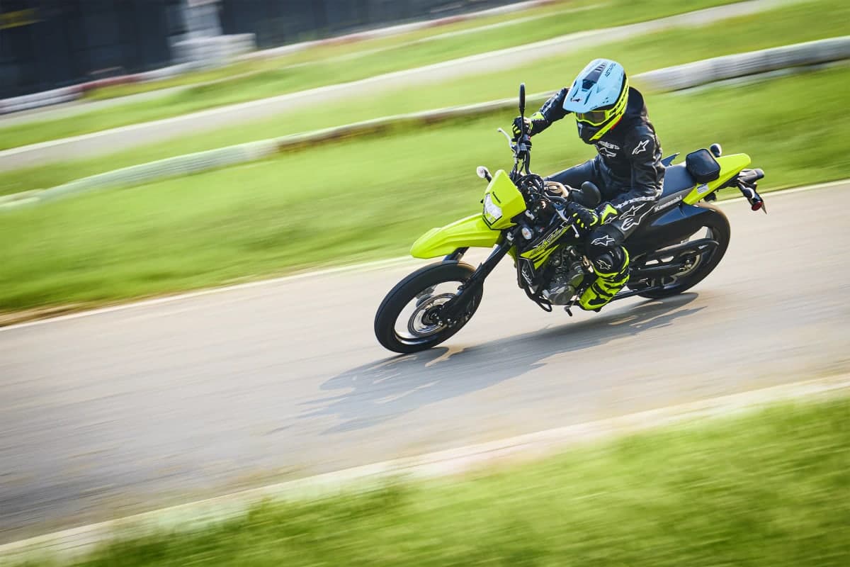 Rider leaning a green KLX300SM through a corner on a kart track