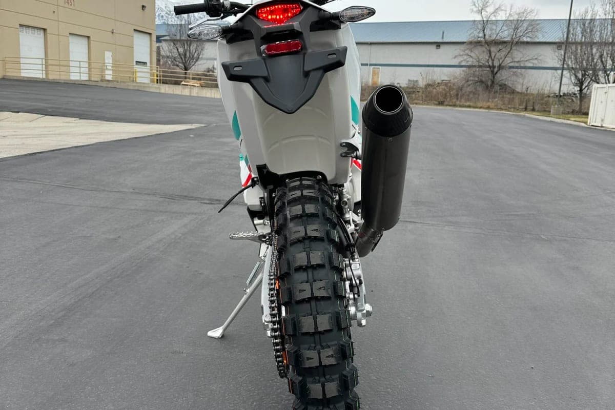 Kove 450 Rally rear-on view in a parking lot showing the LED taillight, black exhaust tip and aggressive knobby rear tire tread