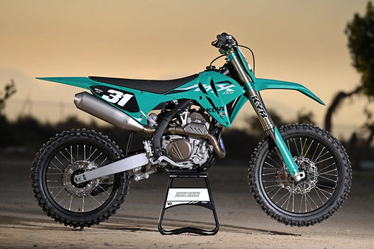 2026 Kove MX250 in teal, dusk-lit left-side profile on a track stand with number 31 plate and KYB-branded forks visible