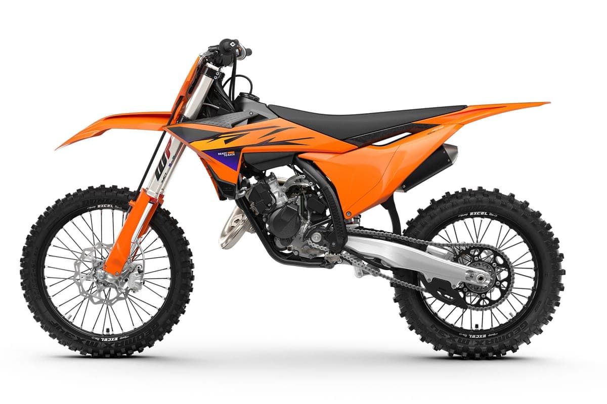 KTM 125 SX left-side studio profile in orange bodywork with black seat, showing the chrome exhaust pipe and spoked wheels with knobby tires