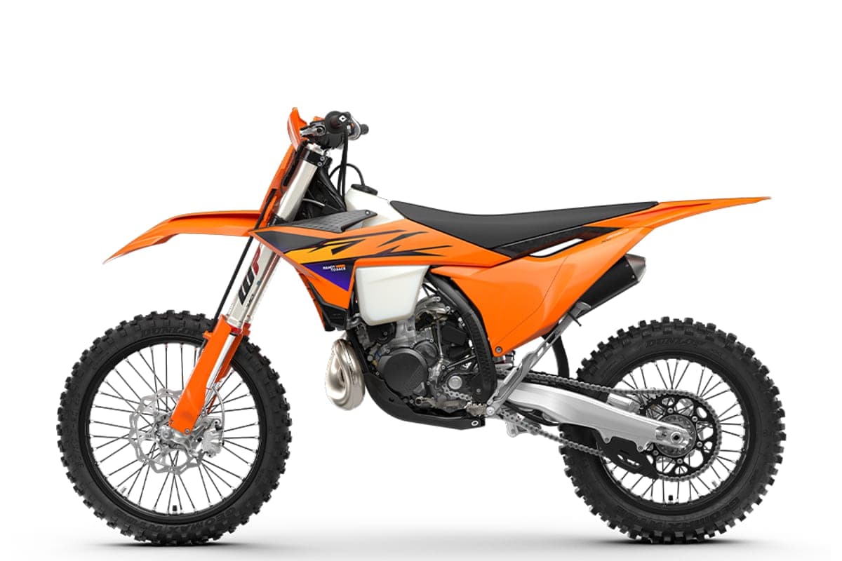 KTM 250 XC left-side studio profile with orange bodywork and black graphics, highlighting the twin exhaust guard and spoked wheels with Dunlop tires