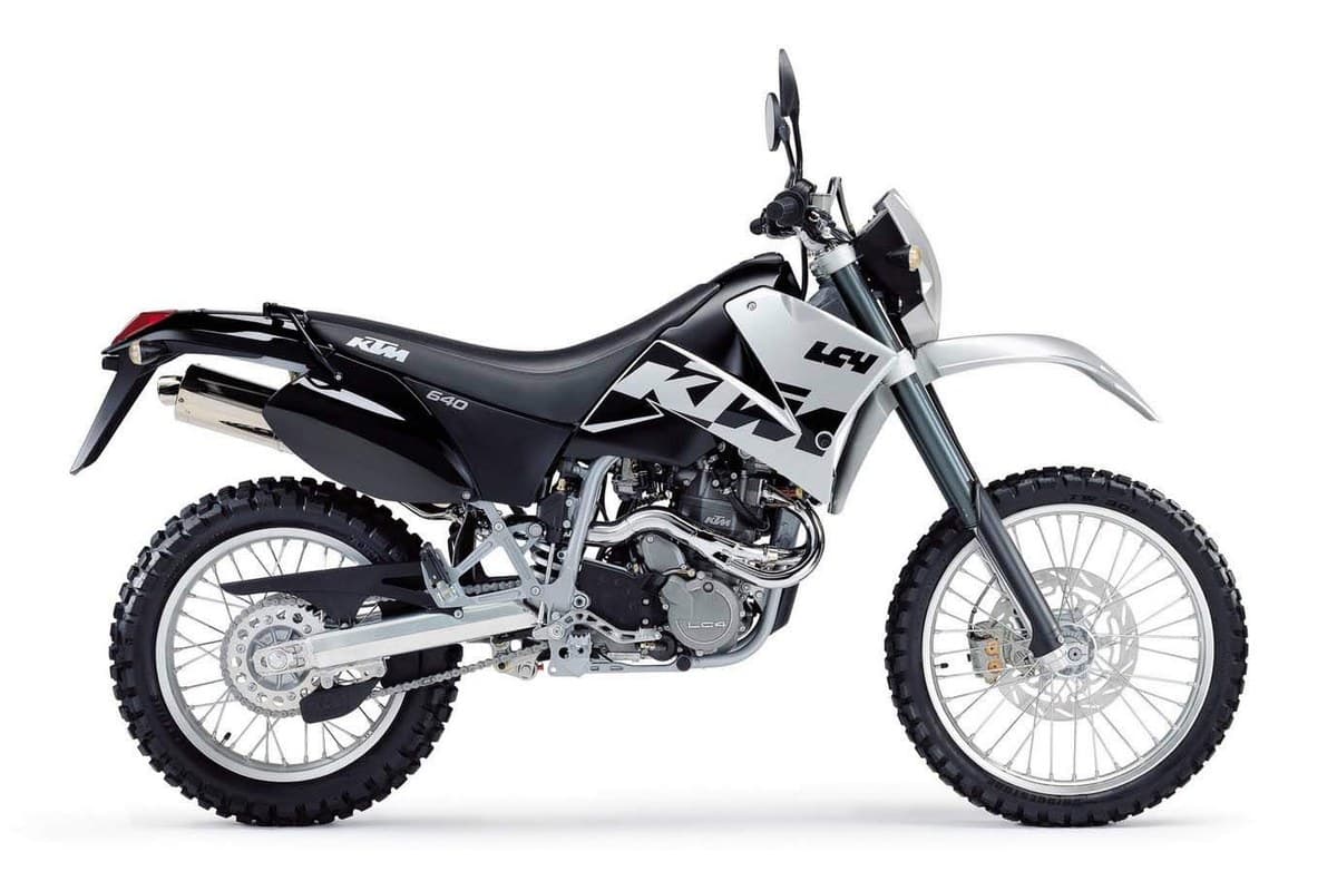 KTM 640 Adventure in black and silver livery, right-side studio profile with fork-mounted headlight fairing and knobby dual-sport tires