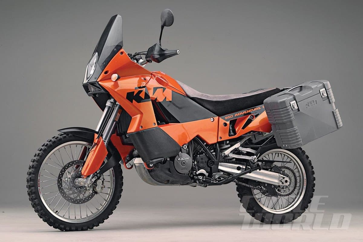 KTM 950 Adventure S in orange and black, side-on profile fitted with a gray hard pannier case, inverted forks and knobby dual-sport tires