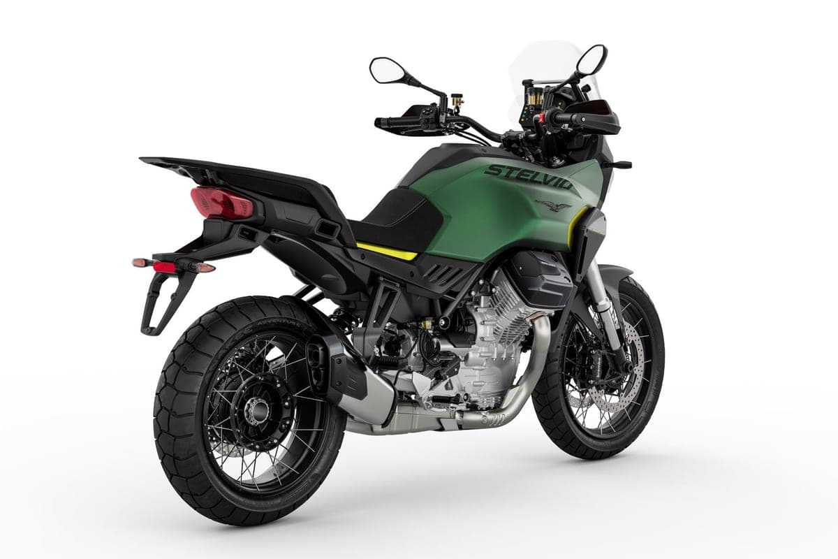 Moto Guzzi Stelvio rear three-quarter studio shot showing the tail rack, red taillight, shaft-drive swingarm and exhaust header