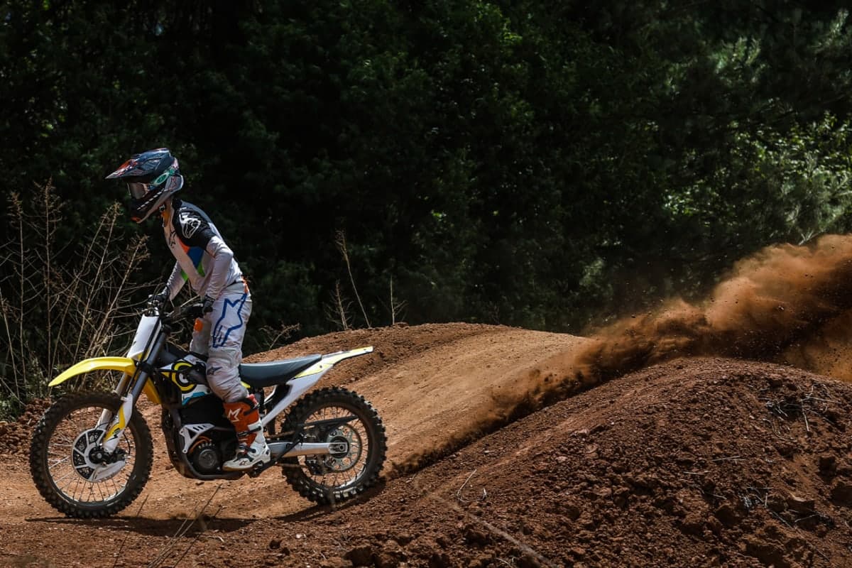 Rider throwing a roost of dirt with a Sur-Ron Storm Bee on a wooded dirt track