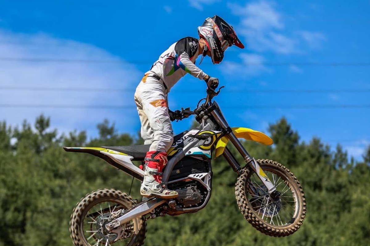Sur-Ron Storm Bee jumped by a rider in full motocross gear against a blue sky