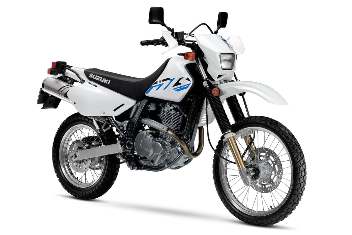 Suzuki DR650S front three-quarter studio view highlighting the round headlight, hand guards, gold fork tubes and spoked wheels