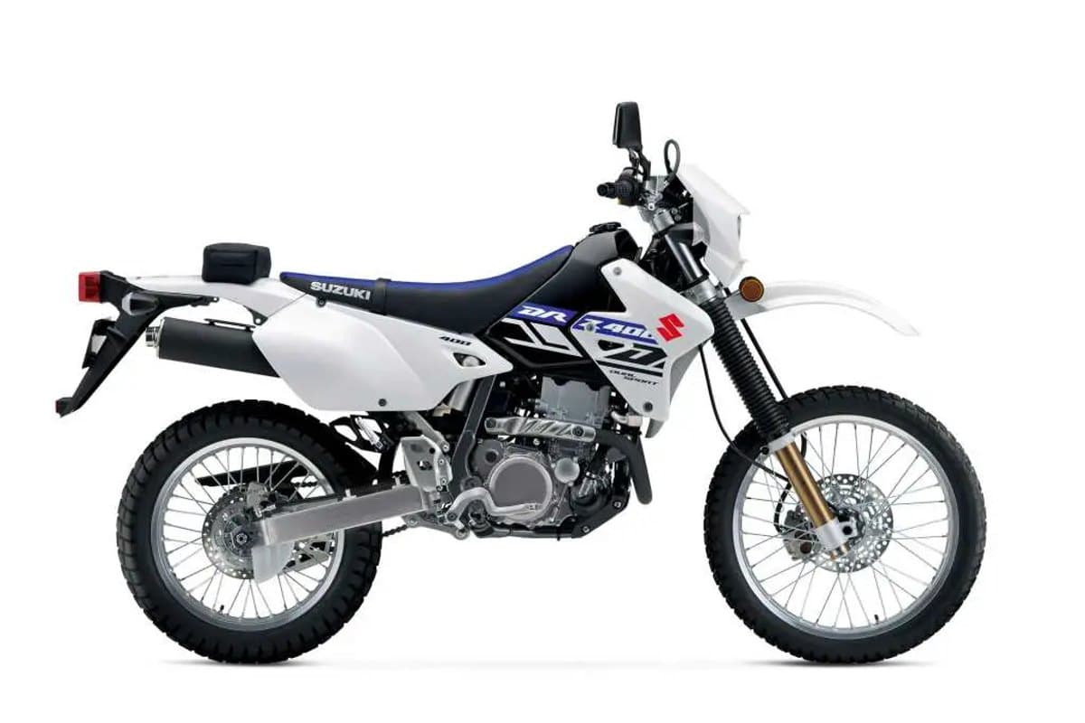 2024 Suzuki DR-Z400S in classic white and blue livery, right-side studio profile showing the twin exhaust, kickstarter and knobby dual-sport tires