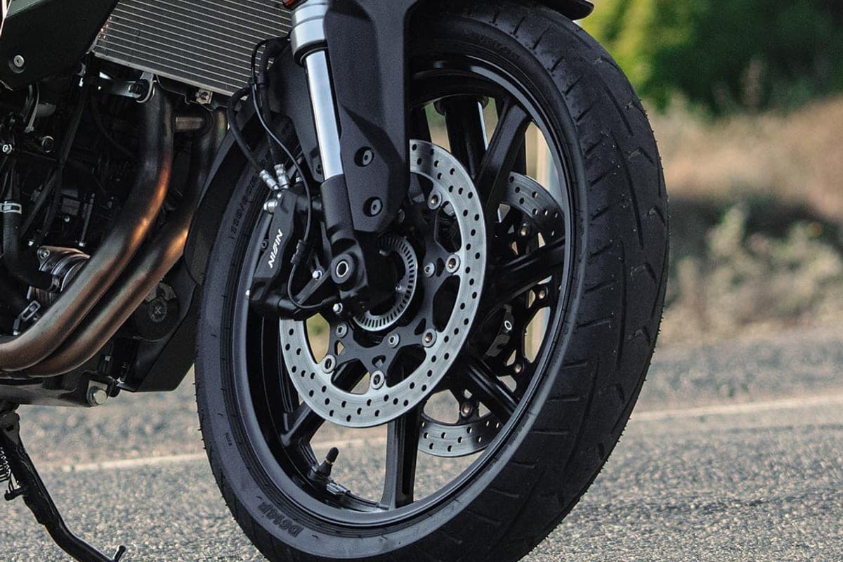 Close-up of the Suzuki V-Strom 800's front end showing the Nissin twin brake calipers, dual discs, inverted fork and Dunlop tire tread
