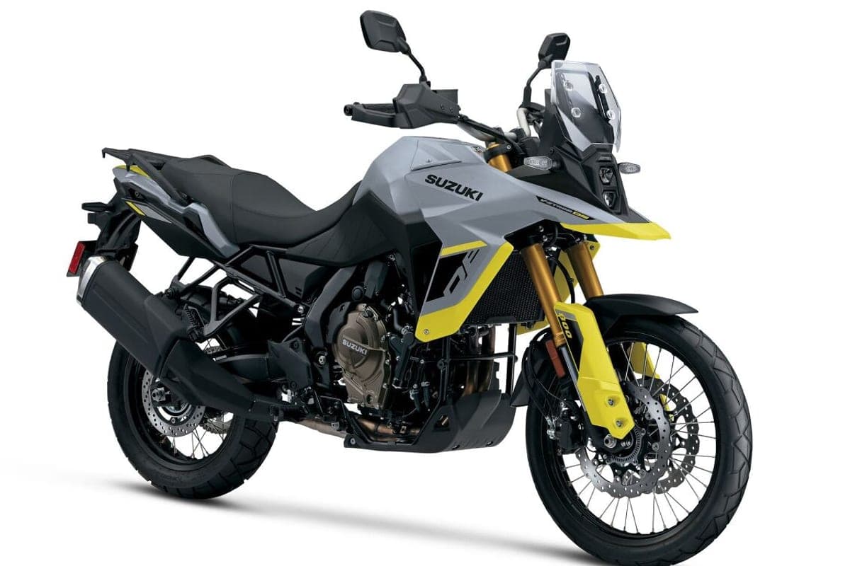 2026 Suzuki V-Strom 800DE in matte grey with yellow accents, front three-quarter studio view highlighting the beak fairing and gold forks
