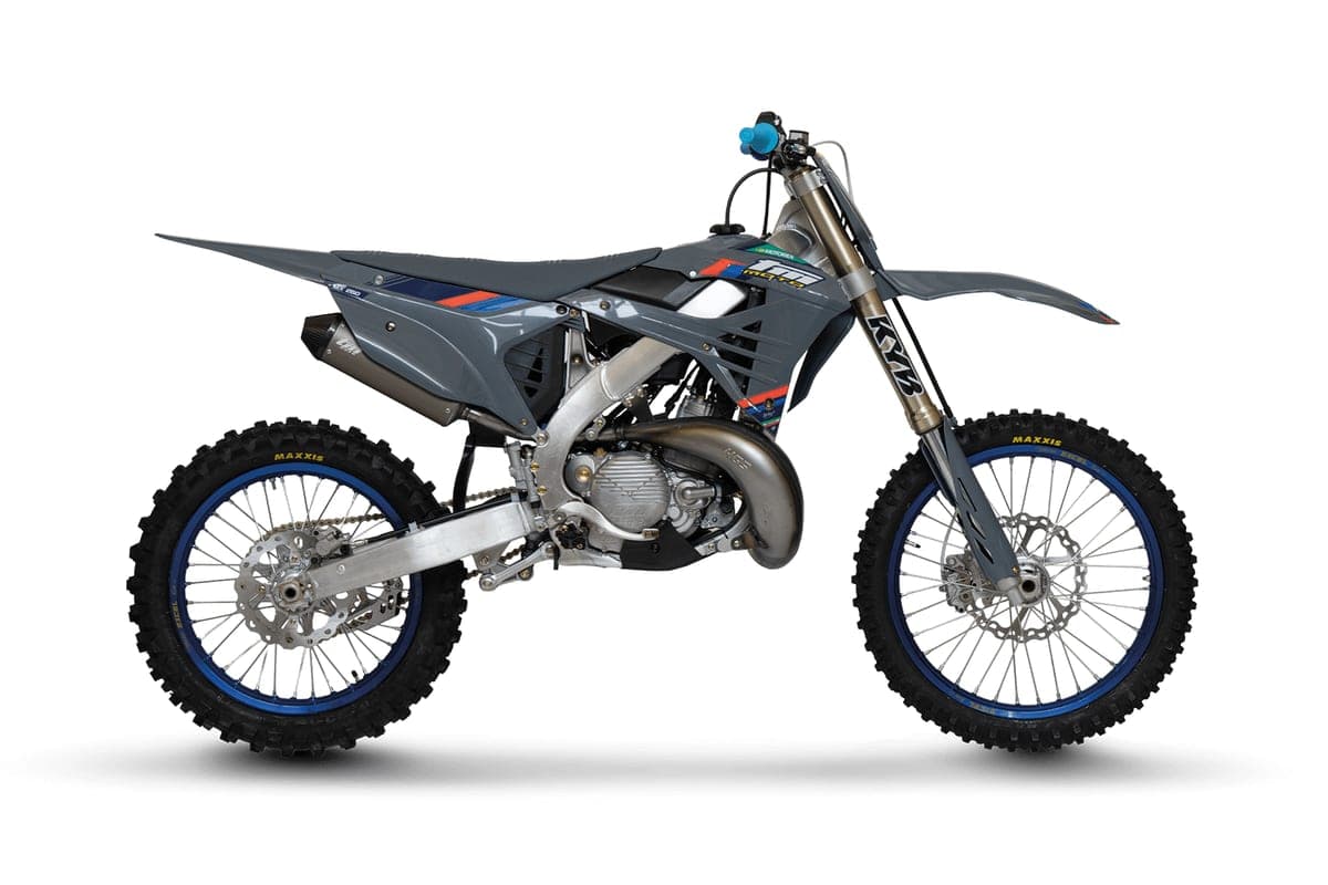 TM MX 250 FI 2T right-side studio profile with red, white and blue graphics, showing the two-stroke exhaust pipe and expansion chamber routing