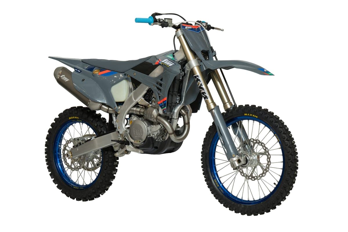 TM MX 450Fi 4T front three-quarter studio close-up in grey, showing the KYB fork legs, radiator, exhaust header and blue-rimmed front wheel