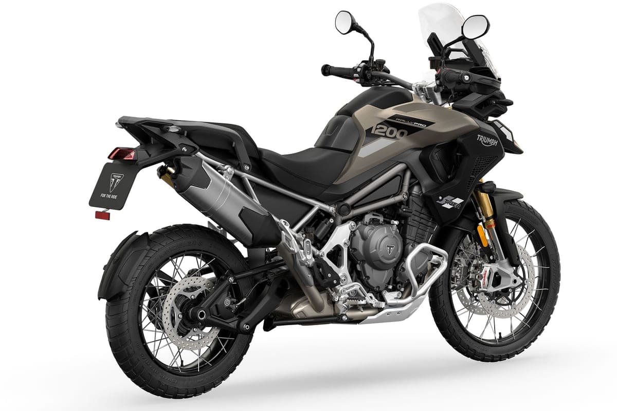 Triumph Tiger 1200 Rally Pro in bronze and black, rear three-quarter studio view showing the twin exhaust cans, gold forks and side luggage mount