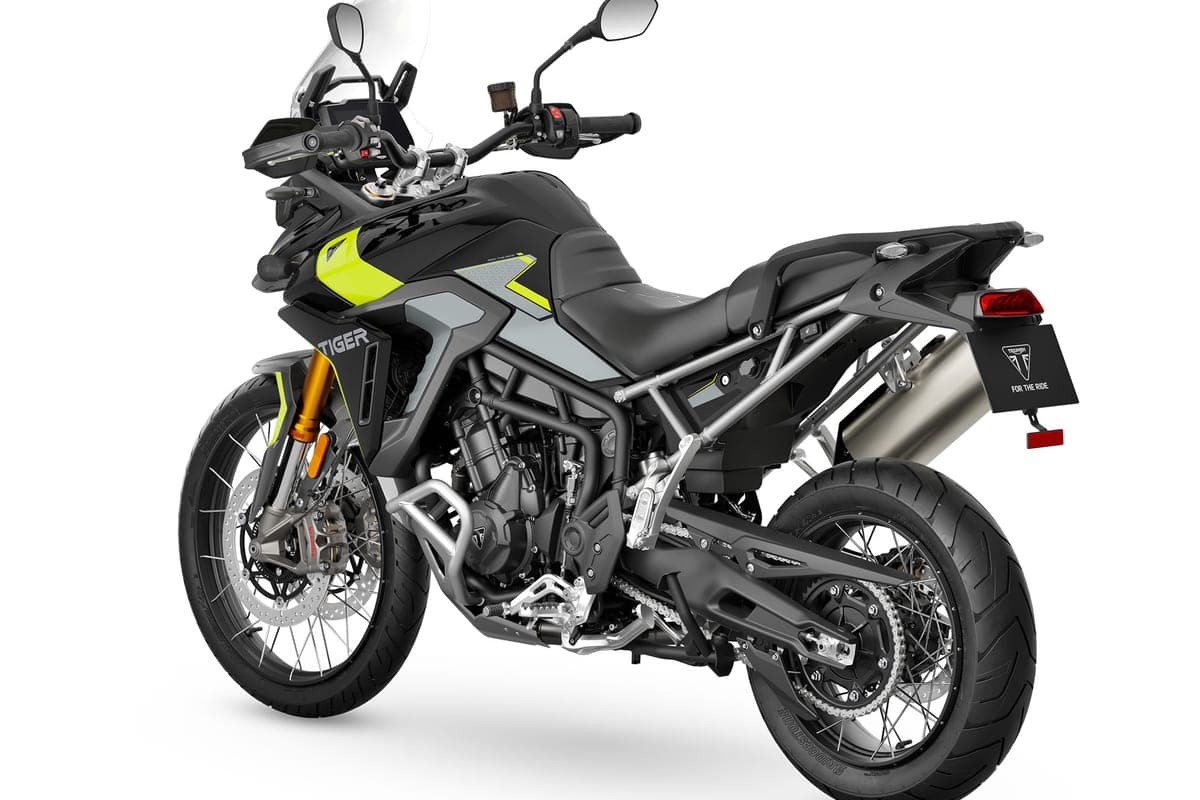Triumph Tiger 900 Rally Pro in black with hi-vis yellow graphics, rear three-quarter studio view showing the stainless exhaust, spoked wheels and luggage rack