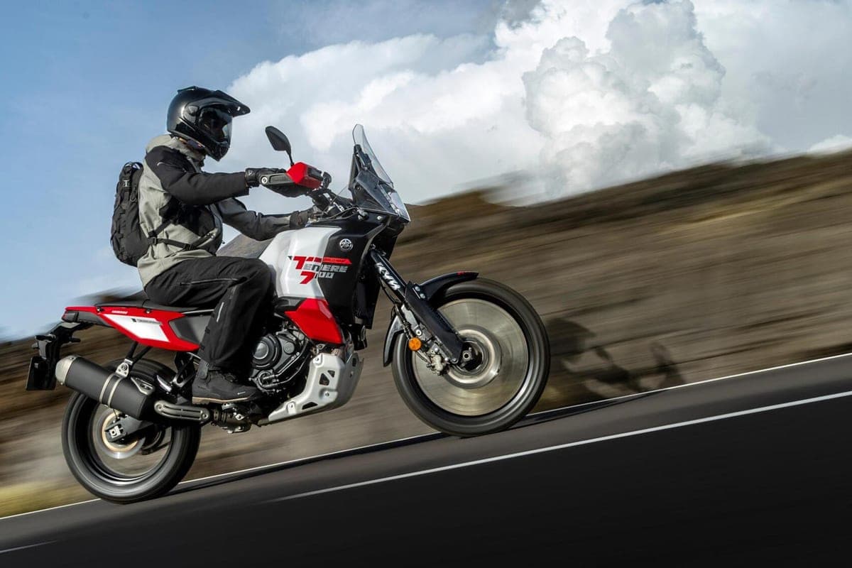 Rider in grey and black gear leaning into a wheelie on the Ténéré 700 World Raid along a paved mountain road