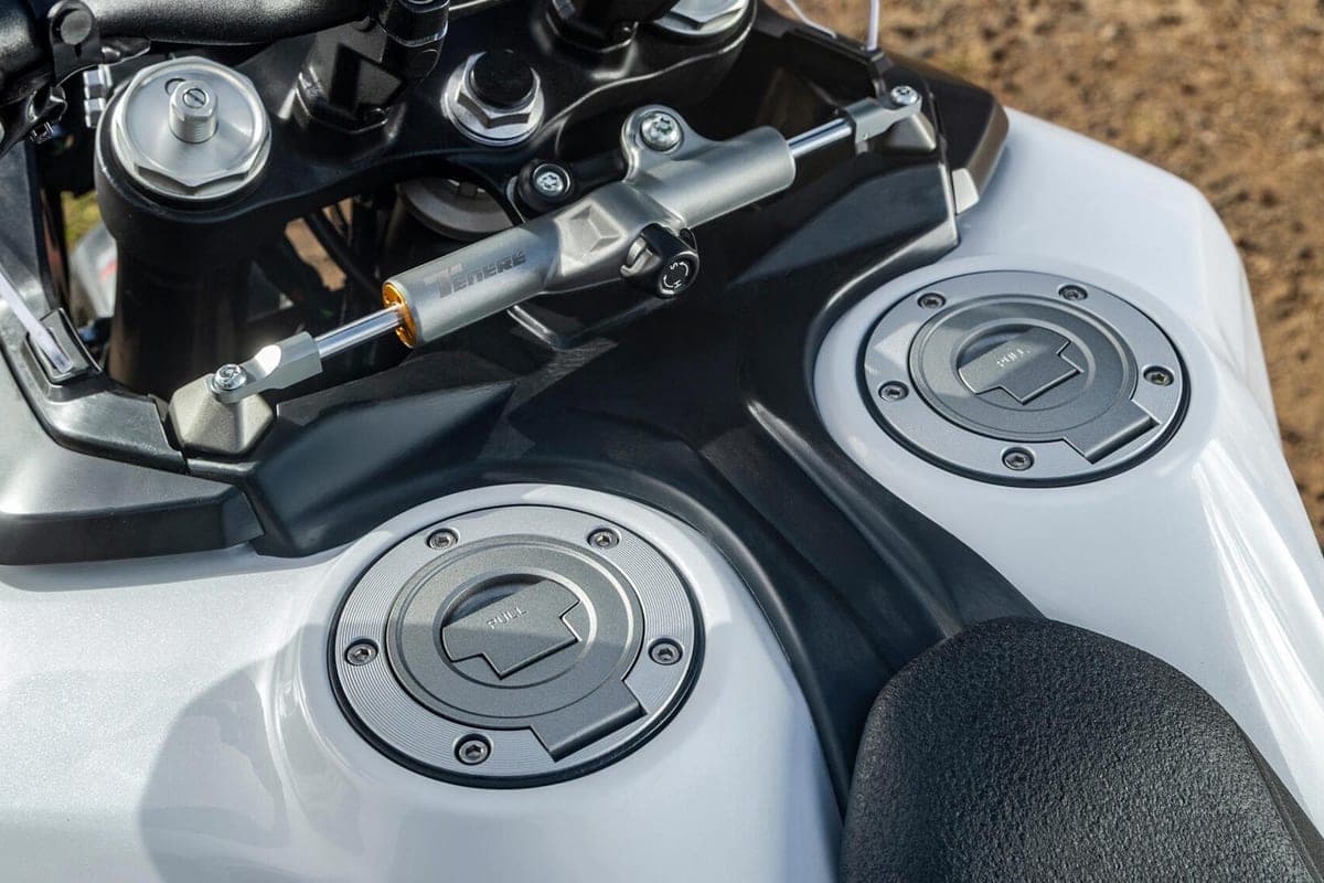 Close-up of the World Raid's dual aluminum fuel tank caps and steering damper mounted beneath the handlebar triple clamp