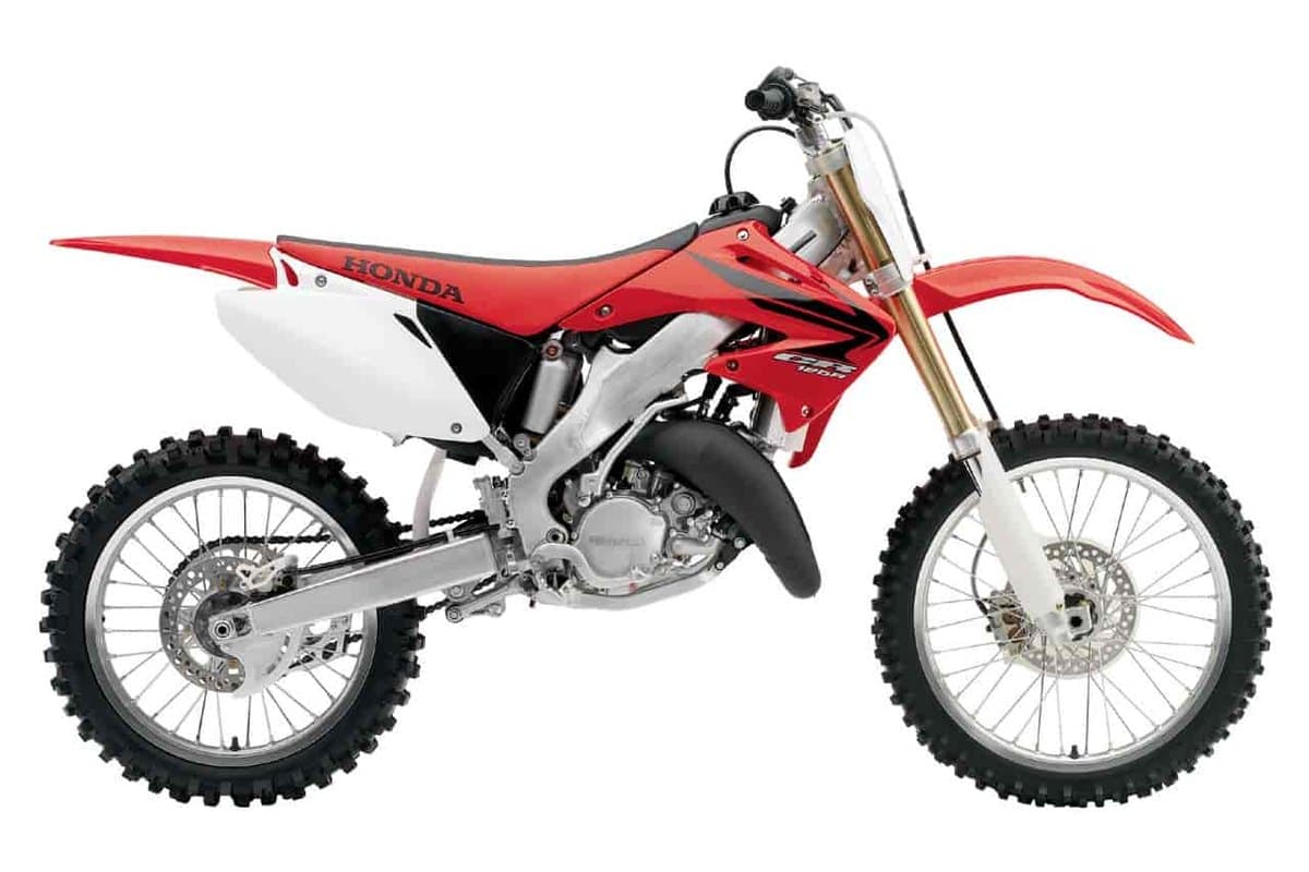 2007 Honda CR125R two-stroke motocross bike in red with white plastics, right-side studio profile showing gold forks and knobby tires