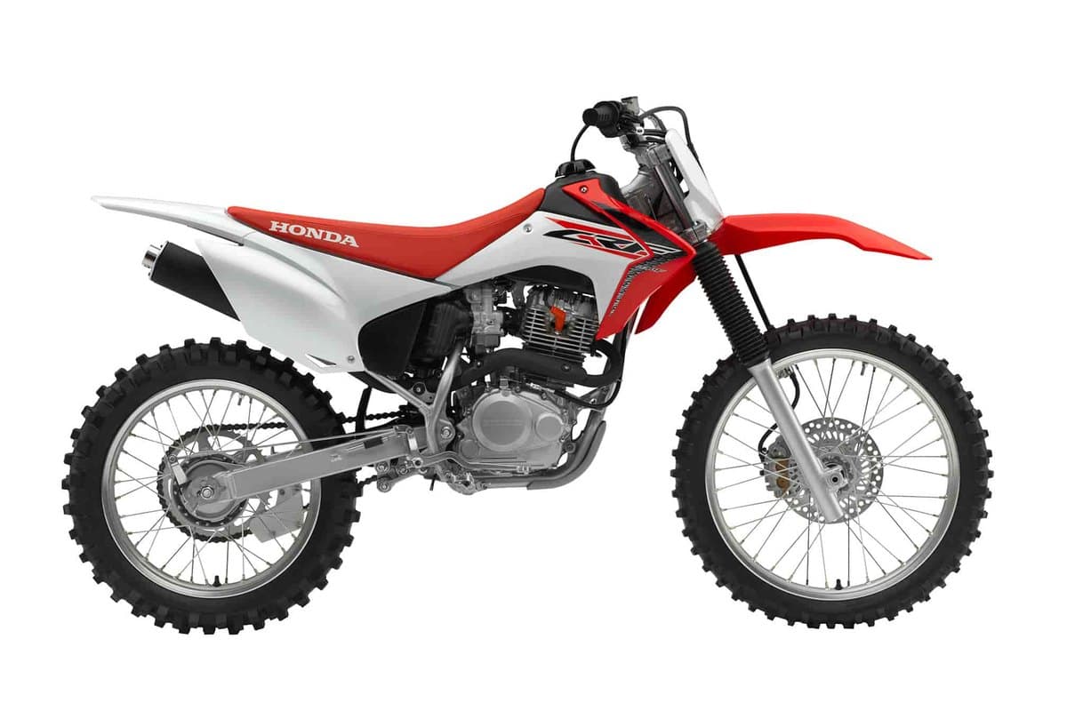 2019 Honda CRF230F dual-sport trail bike in red and white, right-side studio profile showing the black exhaust guard, spoked wheels and long front fender