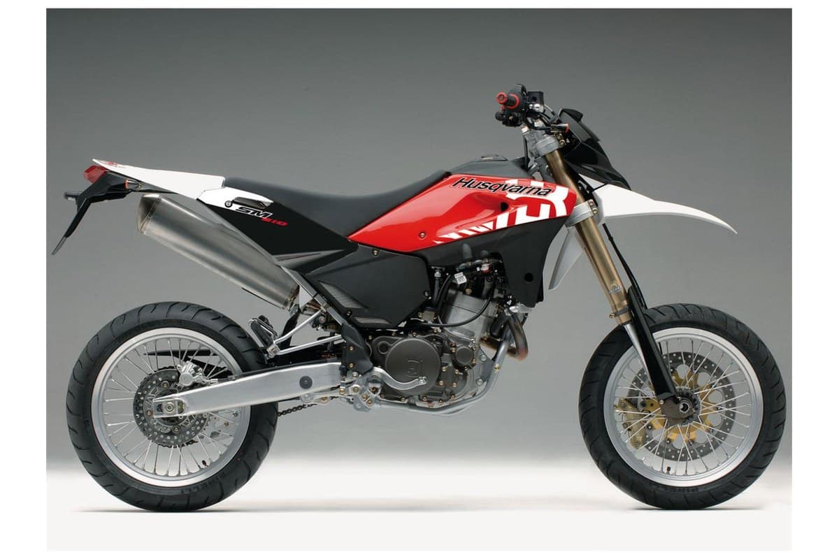 2008 Husqvarna SM 610 supermoto in red, black and white, right-side studio profile showing gold forks, spoked wheels and stubby exhaust