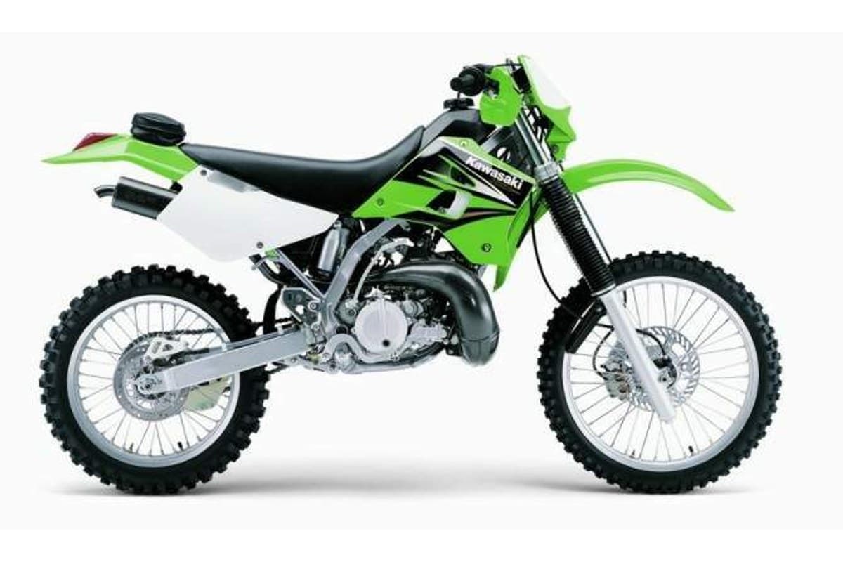 2005 Kawasaki KDX220R enduro in green and white, right-side studio profile showing the two-stroke engine, spoked wheels and black exhaust pipe