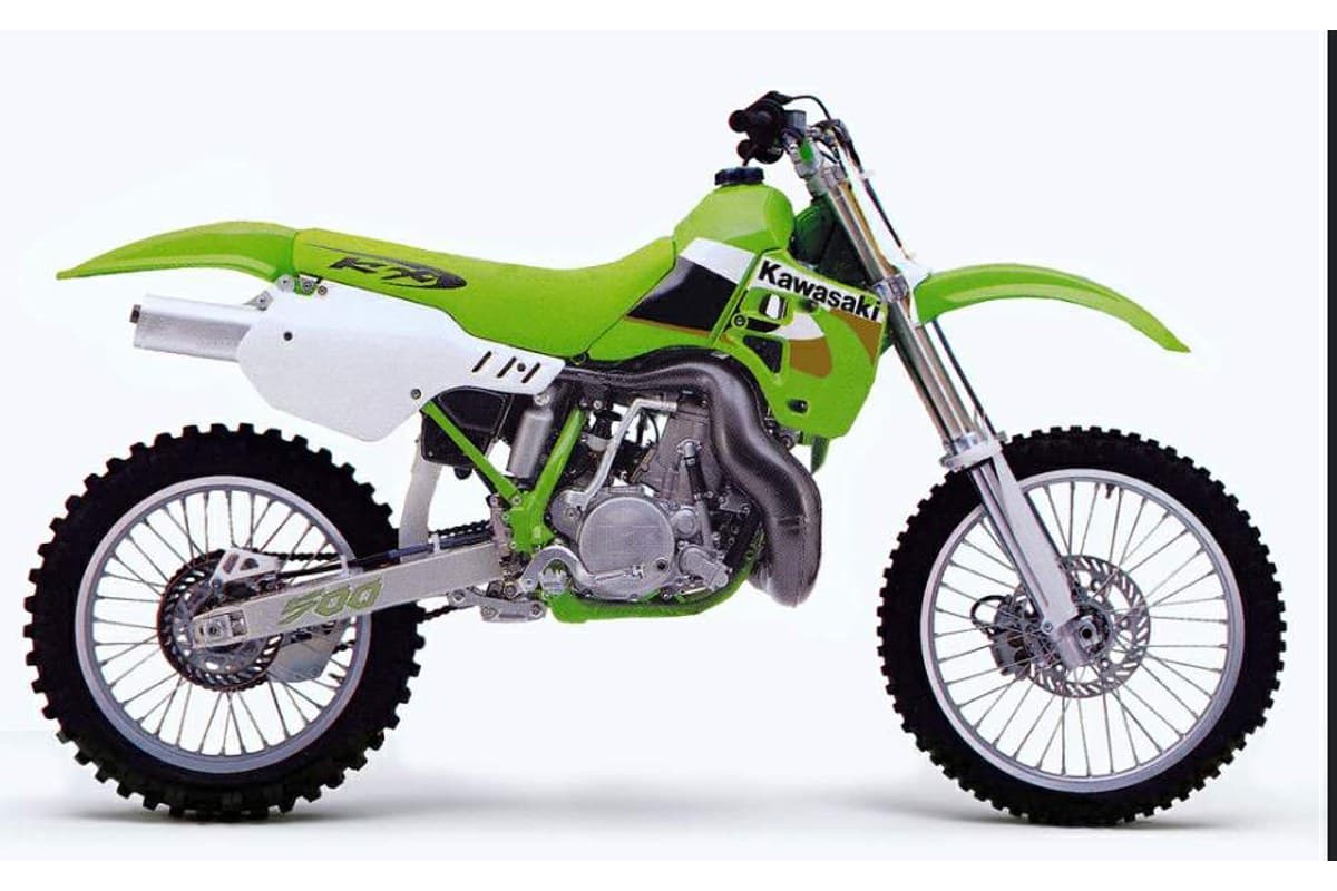 2004 Kawasaki KX500 open-class two-stroke motocross bike in green and white, right-side studio profile with exposed engine and expansion chamber