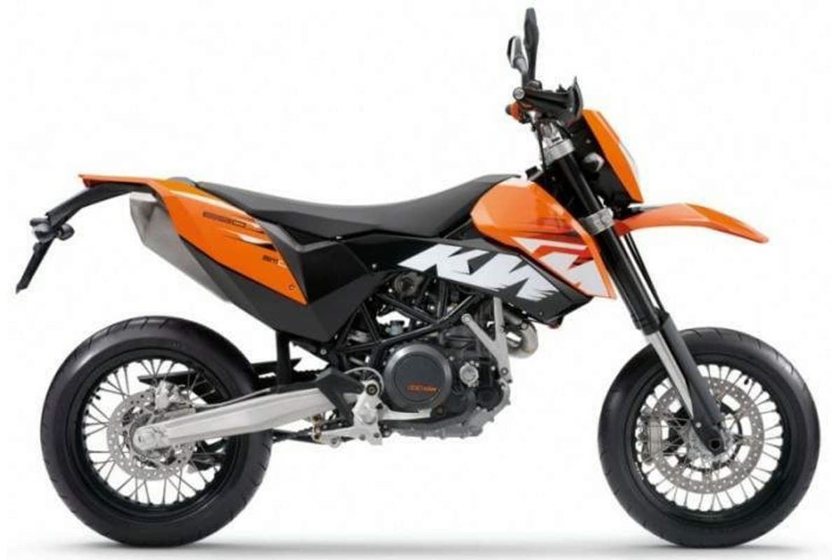 2009 KTM 690 SMC supermoto in orange, black and white, right-side studio profile showing spoked wheels, upside-down forks and stubby exhaust