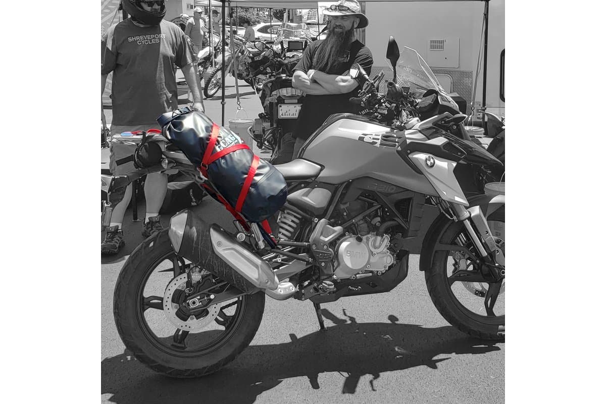 Side view of a BMW G 310 GS carrying a dry bag on red straps above the exhaust