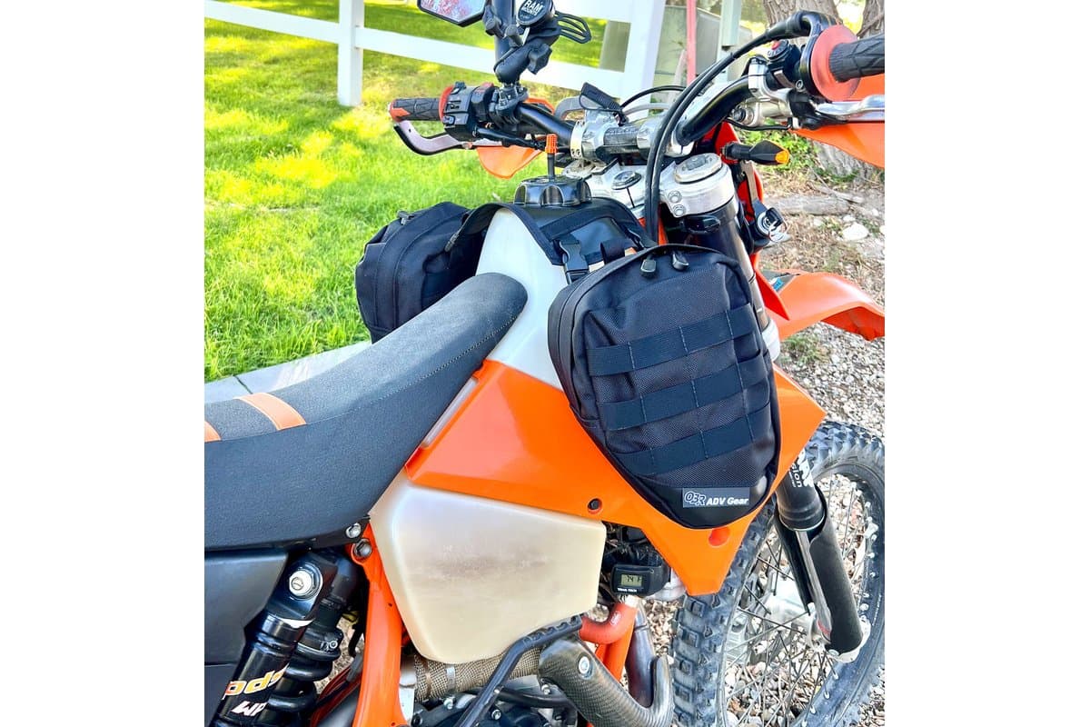 One bag hanging beside the tank of an orange KTM enduro bike