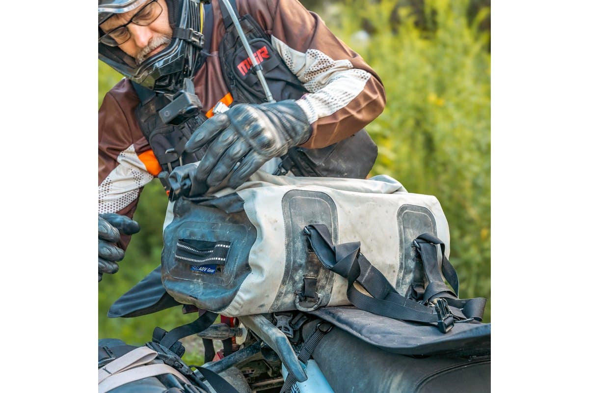 Rider unclipping the duffel strapped across a motorcycle seat