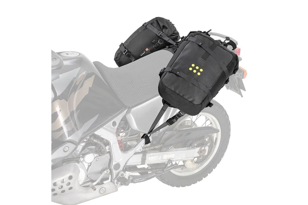 OS-18 Adventure Pack pair mounted on the OS-Base ADV harness, shown over a faded adventure bike