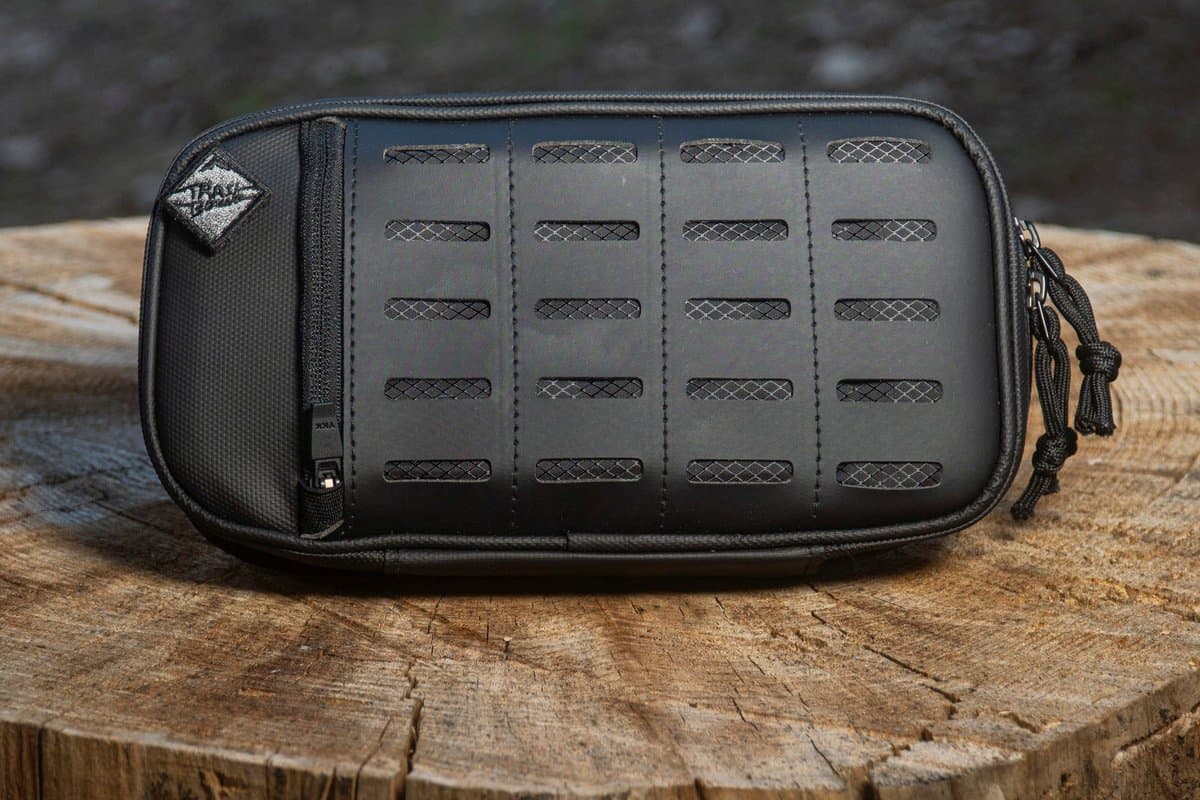 Black Pad Pack Large Expandable with laser-cut MOLLE front on a tree stump