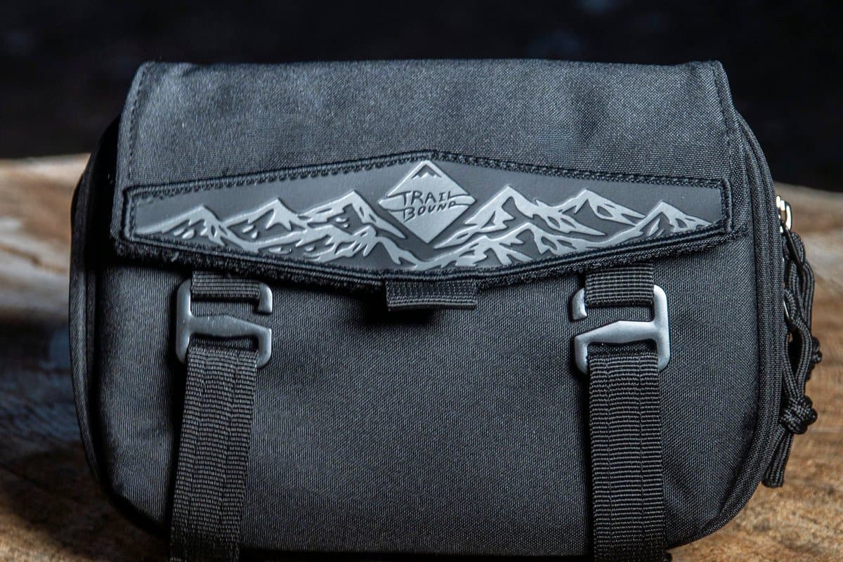 Black Pad Pack Medium 2 Pocket with mountain patch and G-hook straps on a tree stump