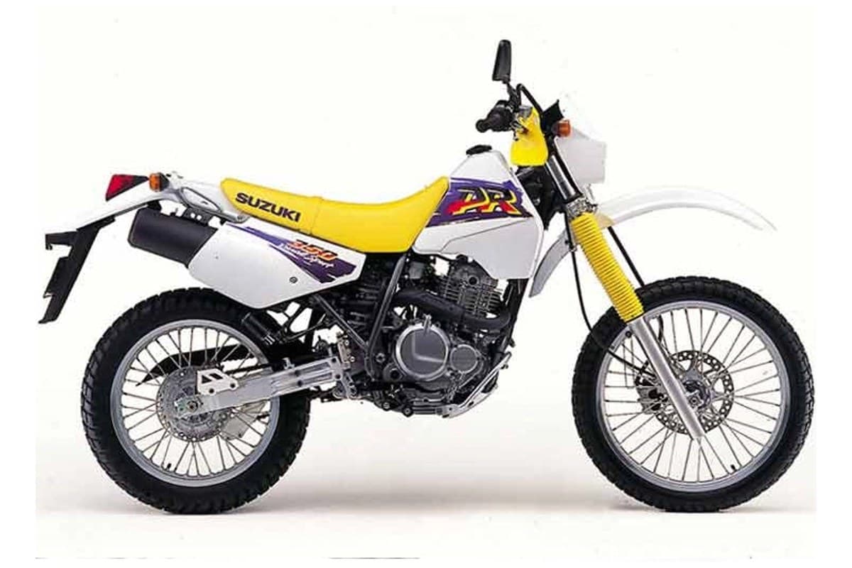 1999 Suzuki DR350SE dual-sport in yellow and white, left-side studio profile on a white background showing spoked wheels and gold-anodized front forks