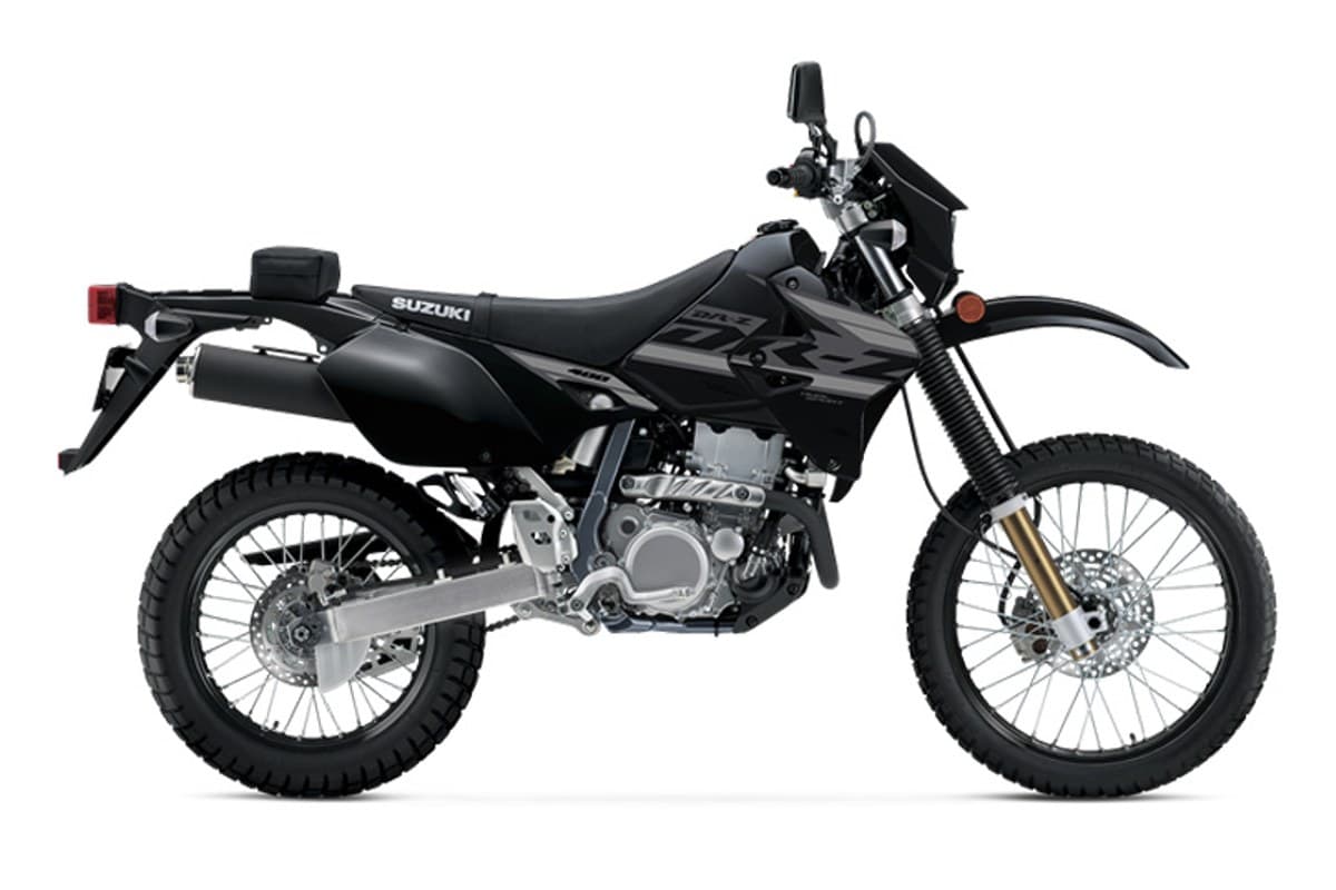 2024 Suzuki DR-Z400S dual-sport in black with grey graphics, left-side studio profile showing spoked wheels, gold forks and rear luggage rack