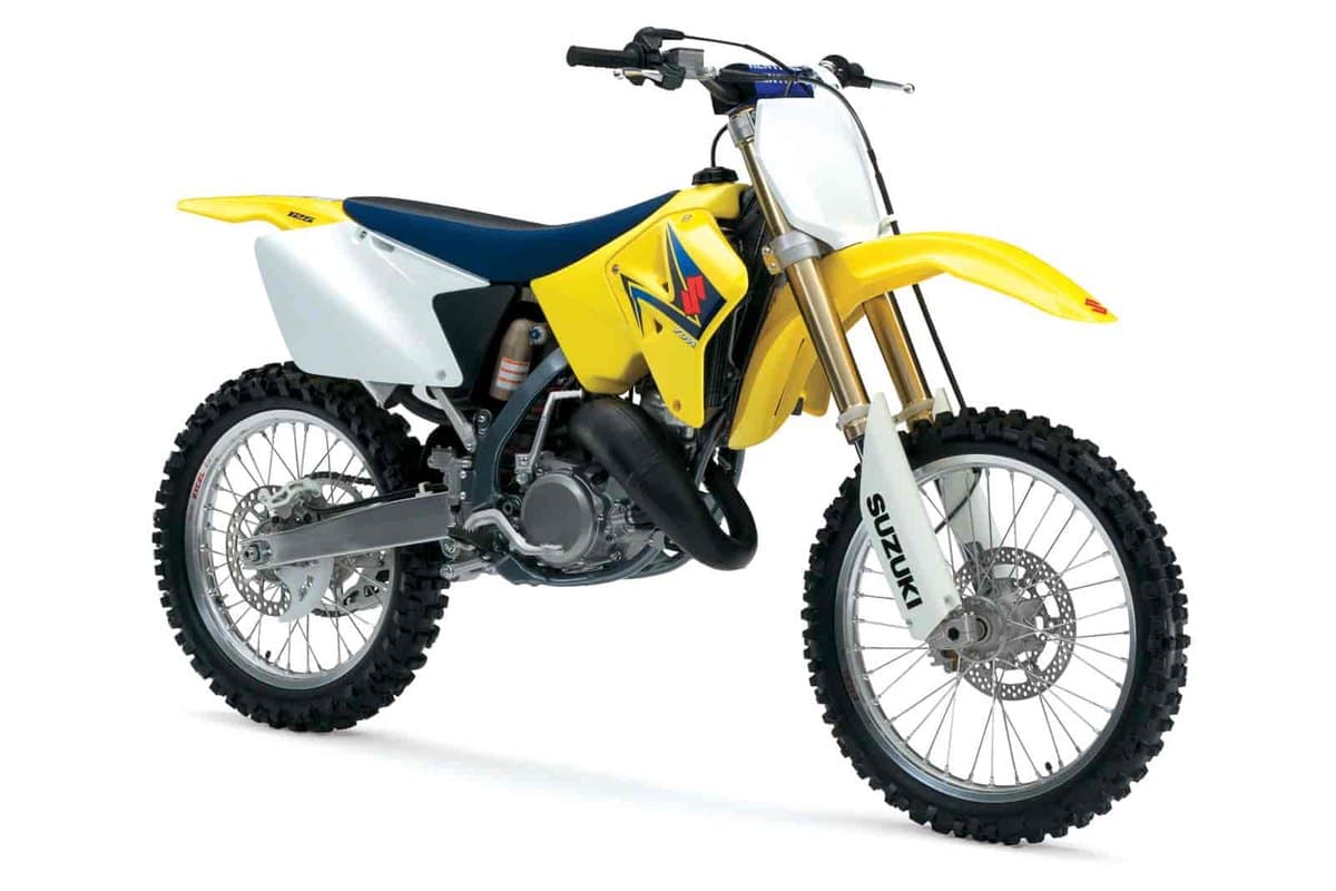 2008 Suzuki RM125 two-stroke motocross bike in yellow with white plastics, front three-quarter studio view showing gold forks and exposed expansion chamber exhaust